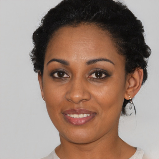 Joyful black young-adult female with short  black hair and brown eyes