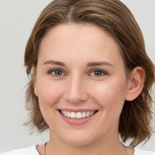 Joyful white young-adult female with medium  brown hair and grey eyes