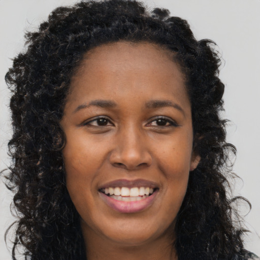 Joyful black young-adult female with long  brown hair and brown eyes