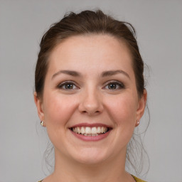 Joyful white young-adult female with medium  brown hair and grey eyes