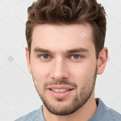 Joyful white young-adult male with short  brown hair and grey eyes