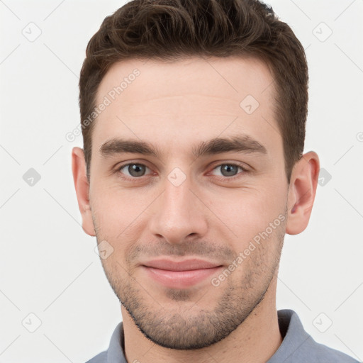 Joyful white young-adult male with short  brown hair and grey eyes