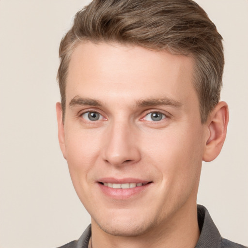 Joyful white young-adult male with short  brown hair and grey eyes