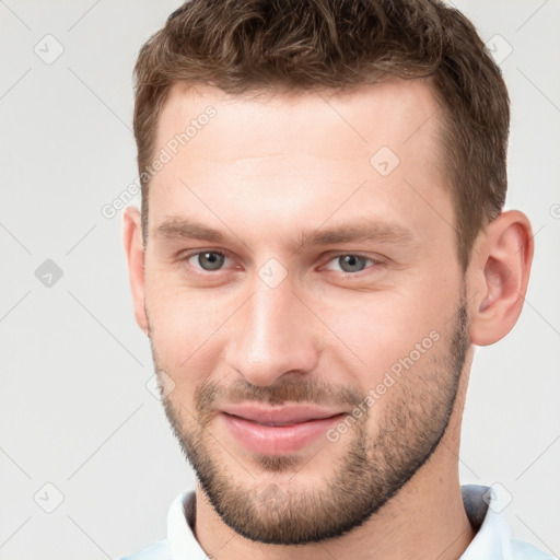 Joyful white young-adult male with short  brown hair and grey eyes