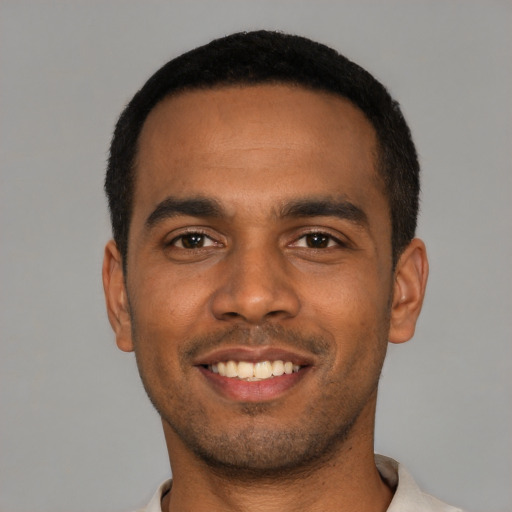 Joyful black young-adult male with short  black hair and brown eyes