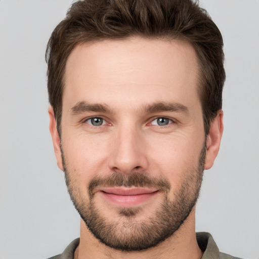 Joyful white young-adult male with short  brown hair and grey eyes