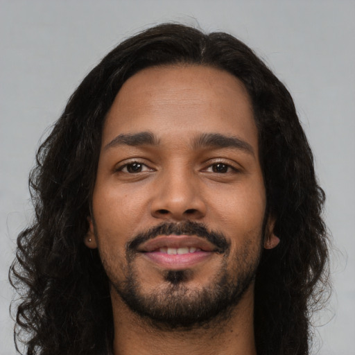 Joyful black young-adult male with long  black hair and brown eyes
