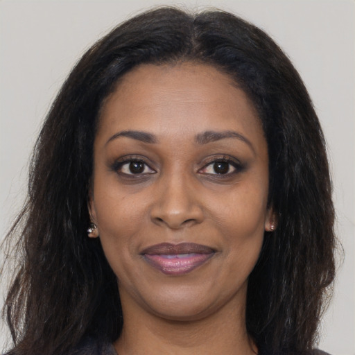 Joyful black young-adult female with long  brown hair and brown eyes
