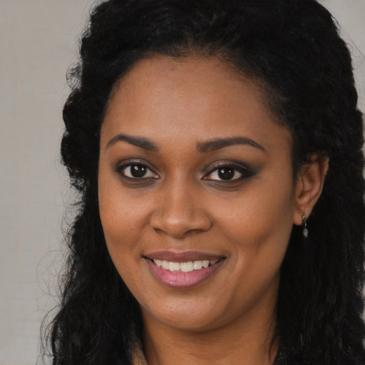 Joyful black young-adult female with long  brown hair and brown eyes