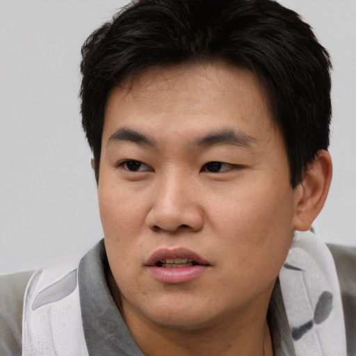 Joyful asian young-adult male with short  brown hair and brown eyes