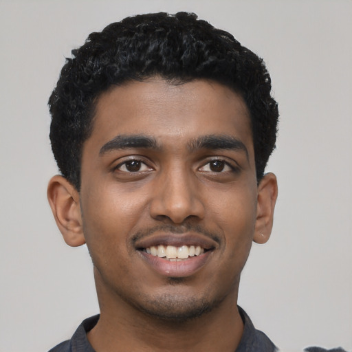 Joyful black young-adult male with short  black hair and brown eyes