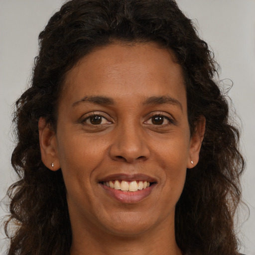 Joyful black adult female with long  brown hair and brown eyes