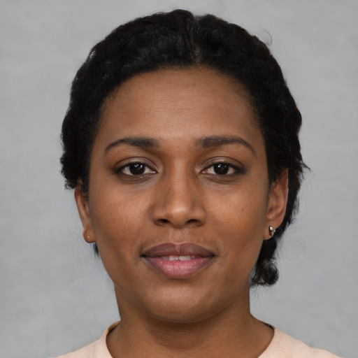 Joyful black young-adult female with short  black hair and brown eyes