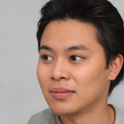 Joyful asian young-adult male with short  brown hair and brown eyes