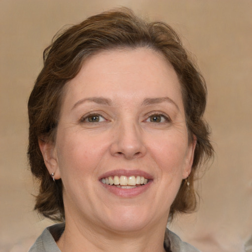 Joyful white adult female with medium  brown hair and green eyes