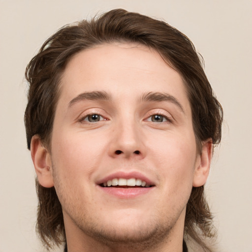 Joyful white young-adult male with medium  brown hair and grey eyes