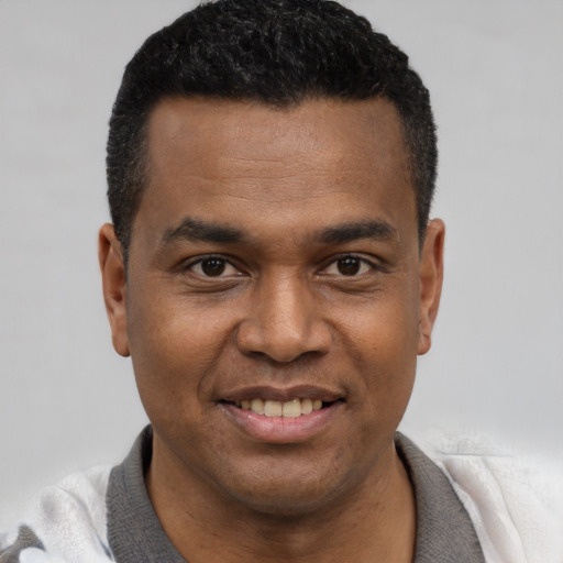 Joyful latino young-adult male with short  black hair and brown eyes