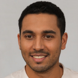 Joyful latino young-adult male with short  black hair and brown eyes