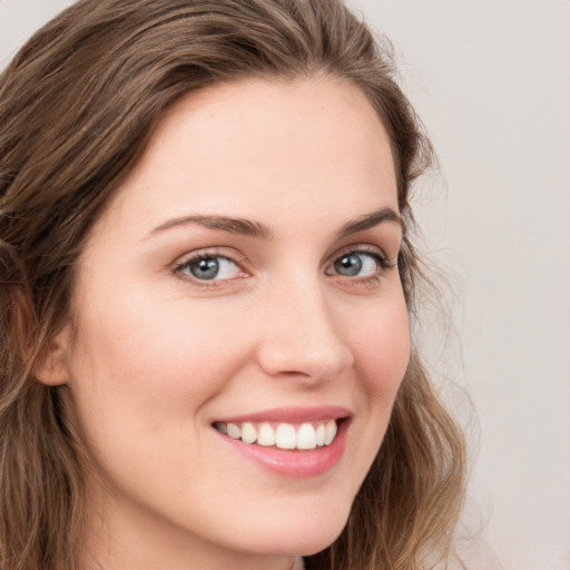 Joyful white young-adult female with long  brown hair and blue eyes