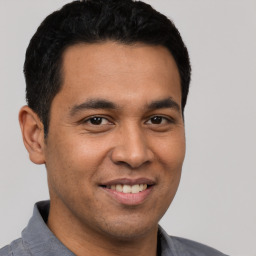 Joyful latino young-adult male with short  black hair and brown eyes