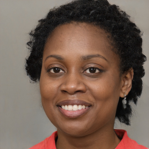 Joyful black young-adult female with long  brown hair and brown eyes