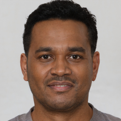 Joyful black young-adult male with short  brown hair and brown eyes