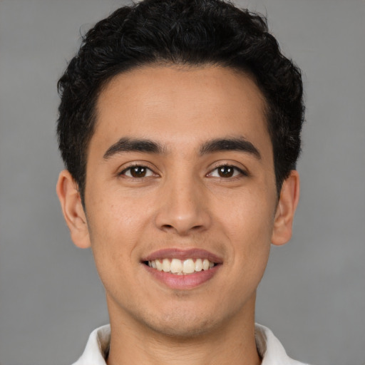 Joyful latino young-adult male with short  brown hair and brown eyes