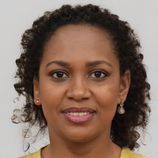 Joyful black young-adult female with long  brown hair and brown eyes