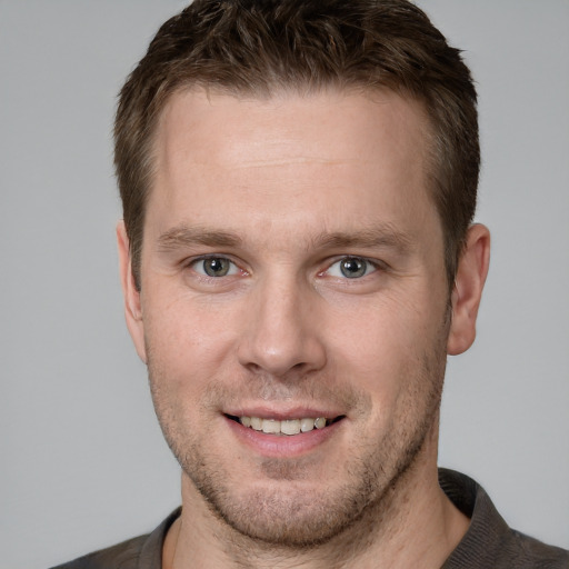 Joyful white young-adult male with short  brown hair and grey eyes