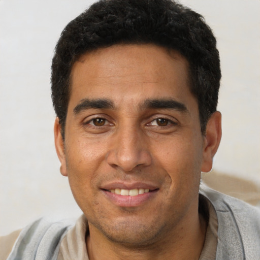 Joyful latino young-adult male with short  black hair and brown eyes