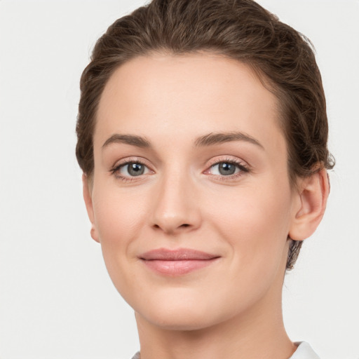 Joyful white young-adult female with short  brown hair and grey eyes