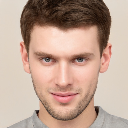 Joyful white young-adult male with short  brown hair and grey eyes