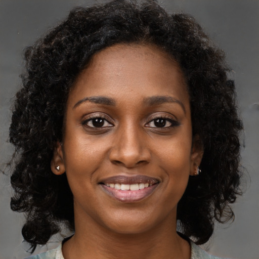 Joyful black young-adult female with long  brown hair and brown eyes