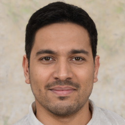 Joyful latino young-adult male with short  black hair and brown eyes