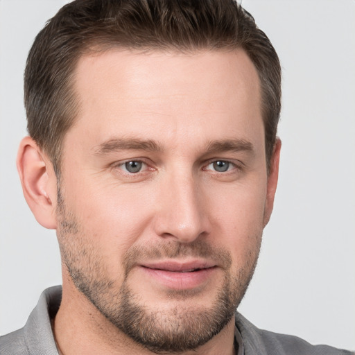 Joyful white young-adult male with short  brown hair and grey eyes