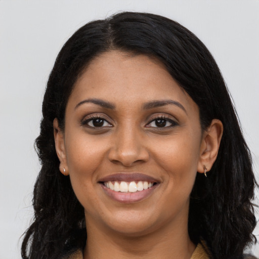 Joyful black young-adult female with long  brown hair and brown eyes