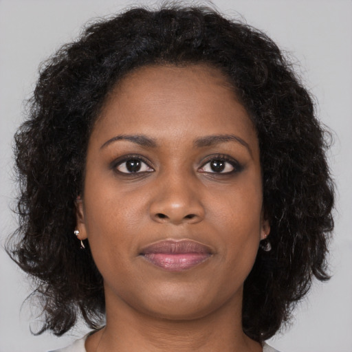 Joyful black young-adult female with long  brown hair and brown eyes