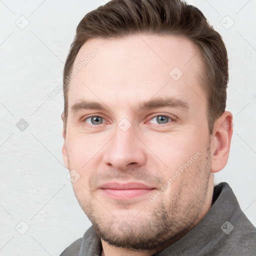 Joyful white young-adult male with short  brown hair and grey eyes