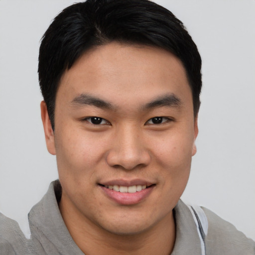Joyful asian young-adult male with short  brown hair and brown eyes