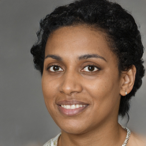 Joyful black young-adult female with short  black hair and brown eyes