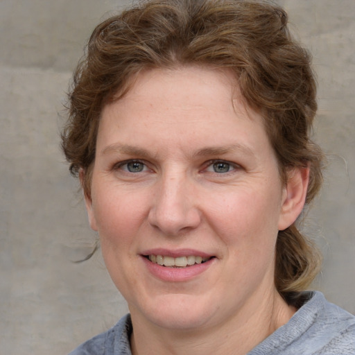 Joyful white adult female with medium  brown hair and blue eyes