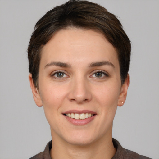 Joyful white young-adult female with short  brown hair and grey eyes