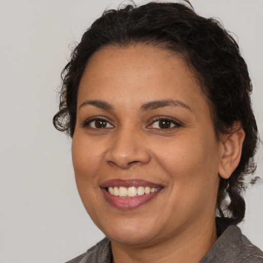 Joyful latino adult female with medium  brown hair and brown eyes
