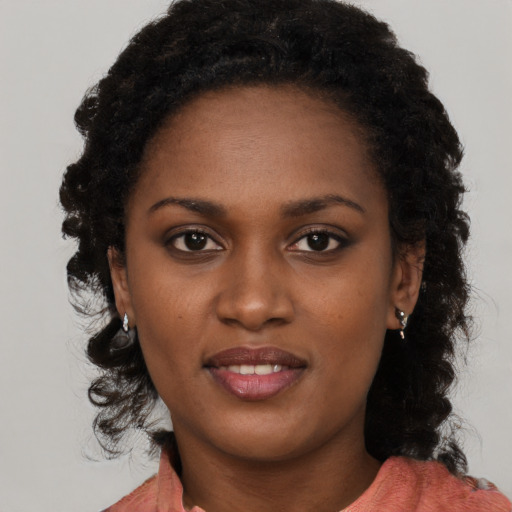 Joyful black young-adult female with long  brown hair and brown eyes