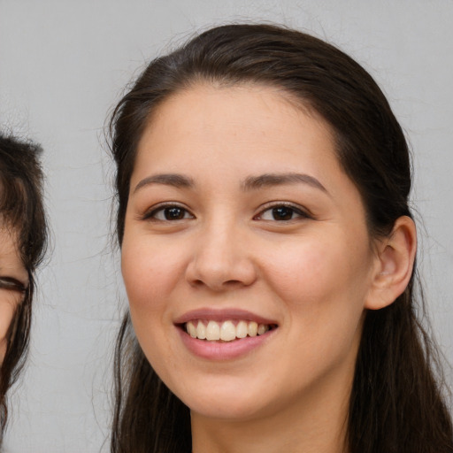 Joyful white young-adult female with long  brown hair and brown eyes