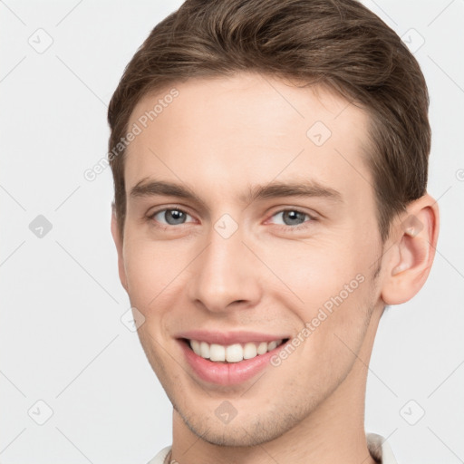 Joyful white young-adult male with short  brown hair and grey eyes