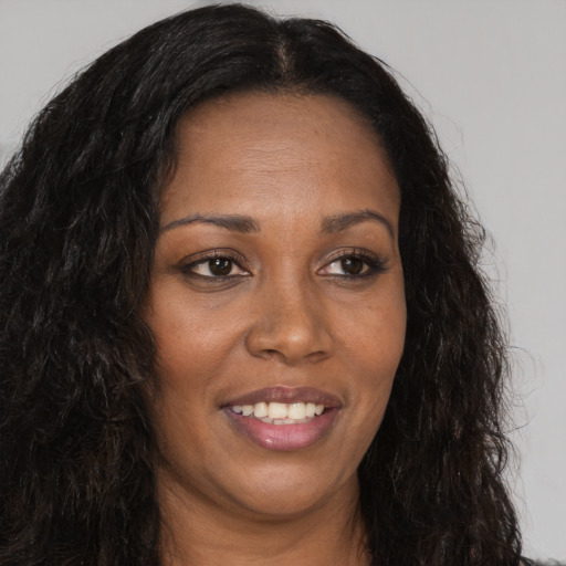Joyful black adult female with long  brown hair and brown eyes