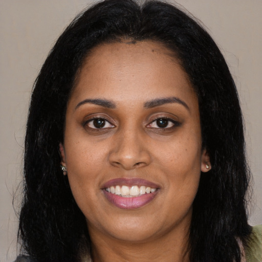 Joyful black young-adult female with long  black hair and brown eyes