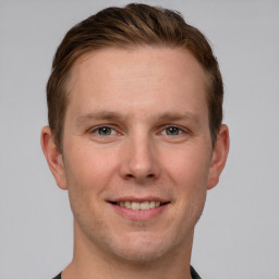 Joyful white young-adult male with short  brown hair and grey eyes