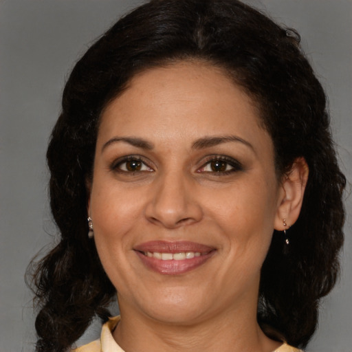 Joyful latino adult female with medium  brown hair and brown eyes